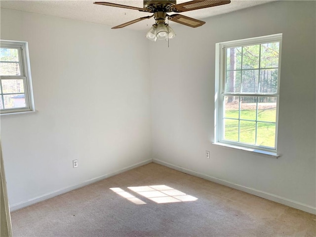 spare room with baseboards, light carpet, a textured ceiling, and a ceiling fan