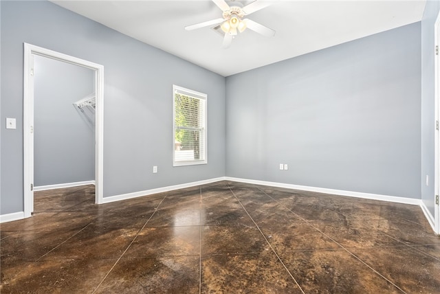 unfurnished bedroom with baseboards, a spacious closet, a closet, and ceiling fan
