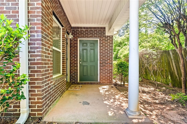 property entrance with fence and brick siding