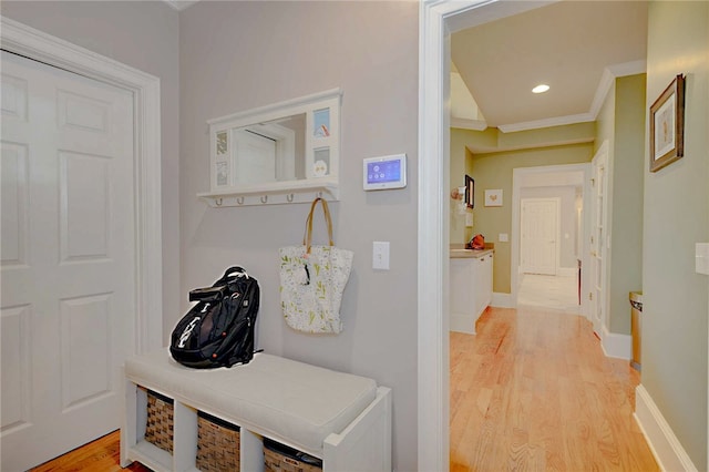 hall with light wood-type flooring, crown molding, baseboards, and recessed lighting