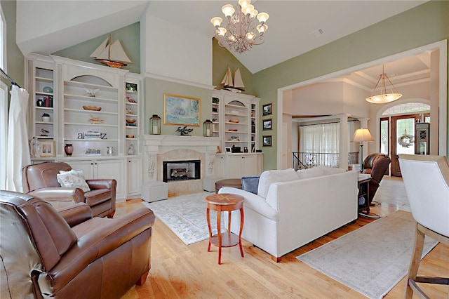 living room featuring a chandelier, light wood-style flooring, a high end fireplace, and high vaulted ceiling
