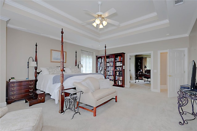 bedroom featuring a raised ceiling, carpet floors, ornamental molding, and a ceiling fan