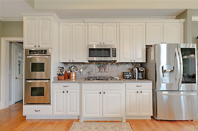 kitchen with stainless steel appliances, light wood-style flooring, light countertops, and backsplash