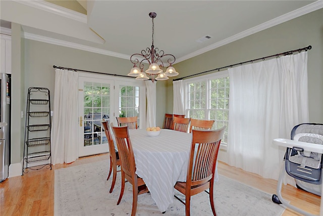 dining room featuring light wood-style flooring, a chandelier, and crown molding