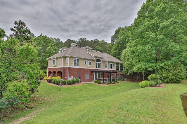 rear view of house featuring brick siding and a lawn