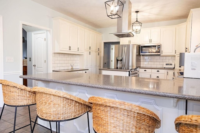 kitchen with white cabinetry, appliances with stainless steel finishes, island range hood, and kitchen peninsula