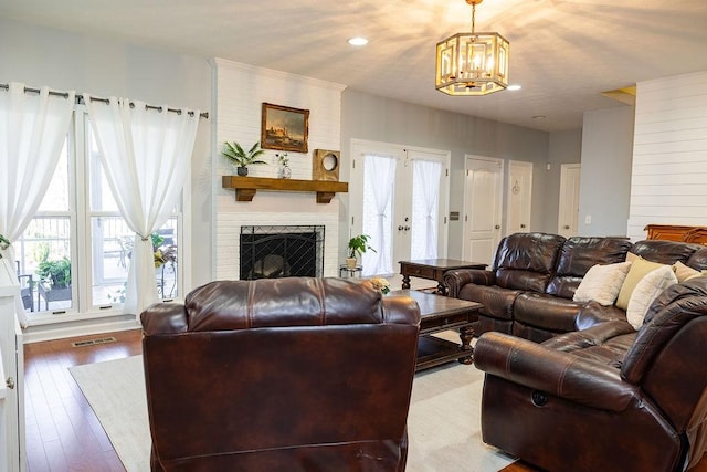 living room featuring light hardwood / wood-style flooring, a brick fireplace, a wealth of natural light, and french doors