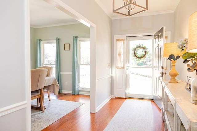 entrance foyer featuring crown molding, hardwood / wood-style floors, and a notable chandelier