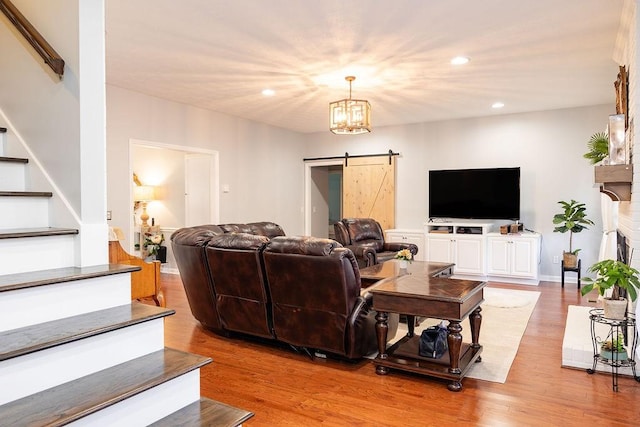 living room with a fireplace, a barn door, light hardwood / wood-style floors, and a notable chandelier