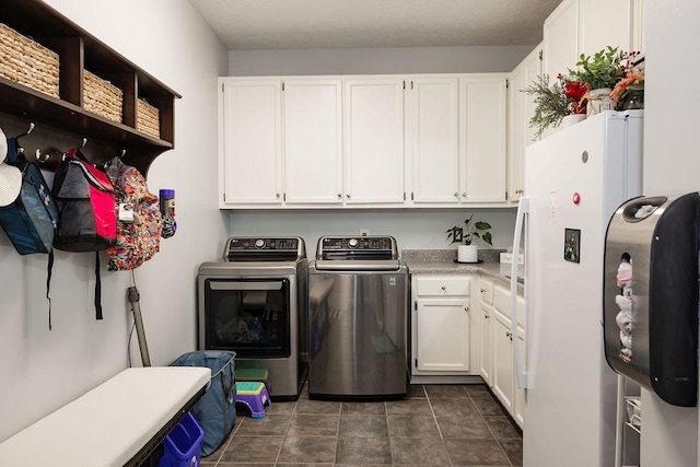 washroom featuring cabinets, dark tile patterned flooring, and washer and clothes dryer