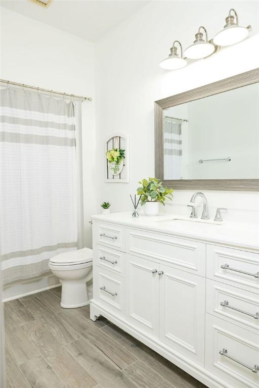 bathroom featuring hardwood / wood-style flooring, vanity, curtained shower, and toilet