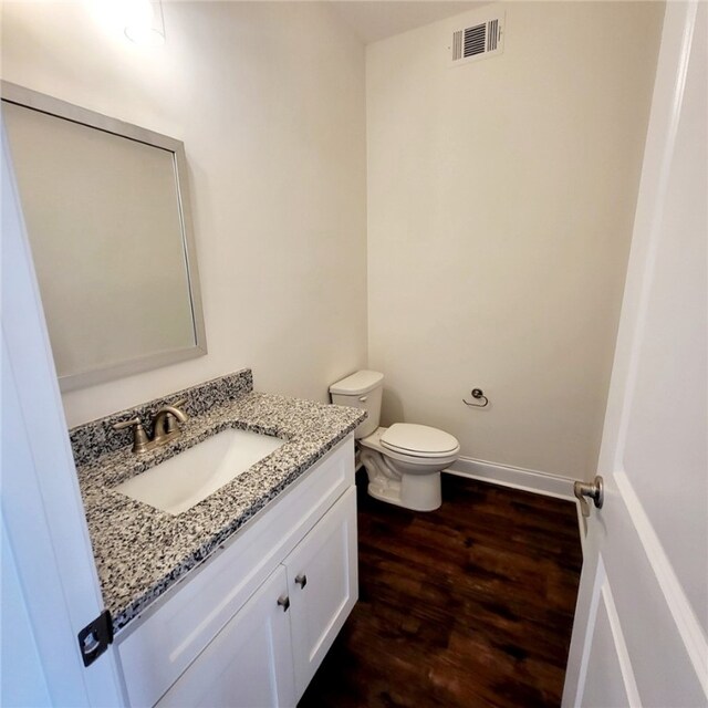 705 Riverside Ests, Lanett, AL 36863 - half bathroom with vanity, wood finished floors, visible vents, baseboards, and toilet