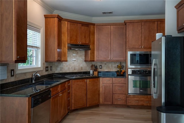 1714 Vfw Rd, Auburn, AL 36830 - kitchen with stainless steel appliances, a sink, under cabinet range hood, brown cabinets, and dark stone counters