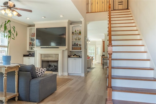 1714 Vfw Rd, Auburn, AL 36830 - stairs with a ceiling fan, crown molding, a tiled fireplace, wood finished floors, and recessed lighting