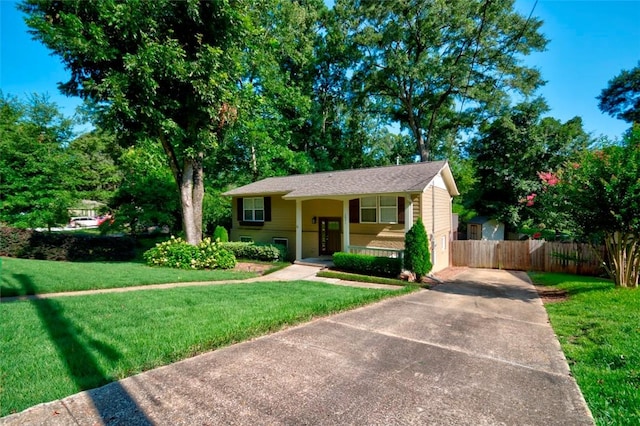 bi-level home featuring driveway, fence, and a front lawn