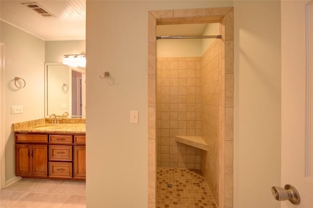 bathroom with tile patterned floors, tiled shower, vanity, and visible vents