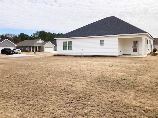 back of property with roof with shingles and a detached garage