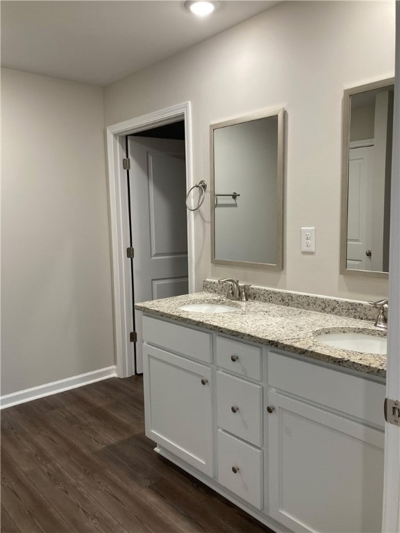 bathroom with double vanity, a sink, baseboards, and wood finished floors