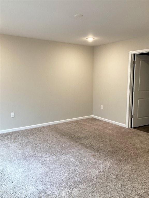 unfurnished room with dark colored carpet and baseboards