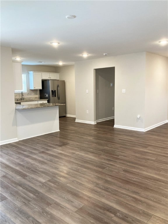 unfurnished living room featuring baseboards and dark wood-style flooring