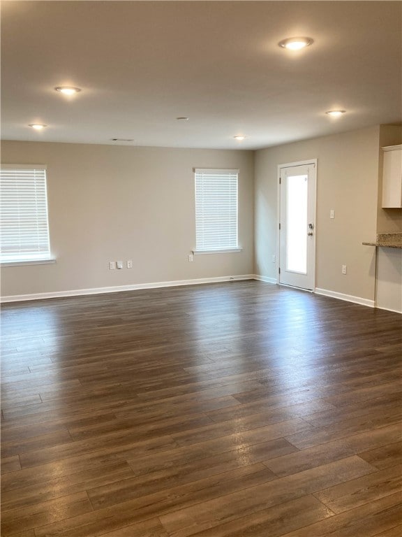 unfurnished living room with baseboards, dark wood-style flooring, and recessed lighting