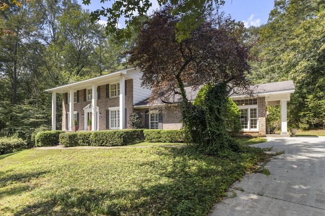 neoclassical home featuring a front lawn and brick siding