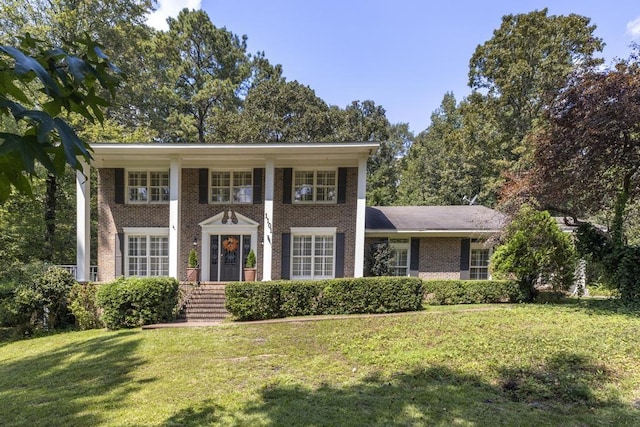 neoclassical home featuring brick siding and a front yard