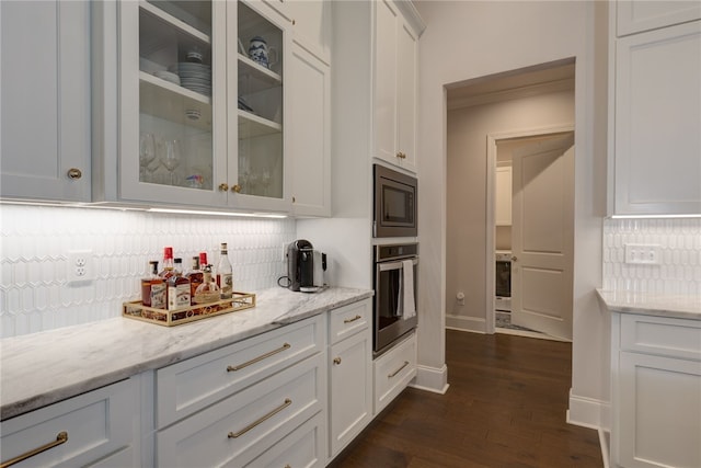 kitchen featuring appliances with stainless steel finishes, white cabinetry, backsplash, and light stone counters