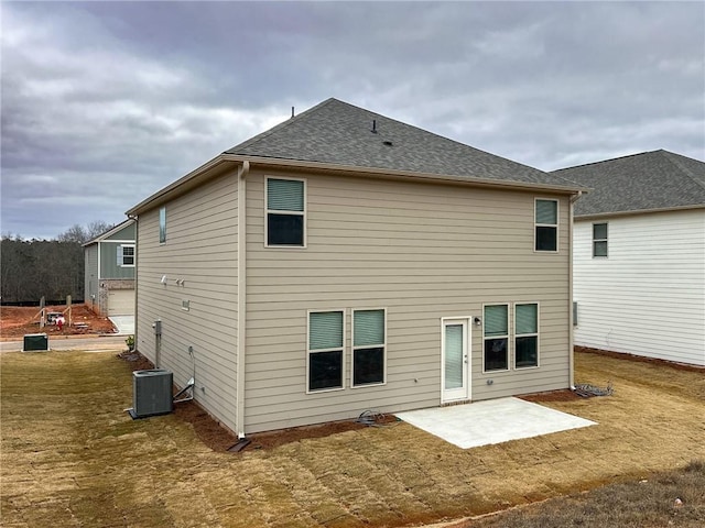 back of property with a patio, a yard, a shingled roof, and cooling unit