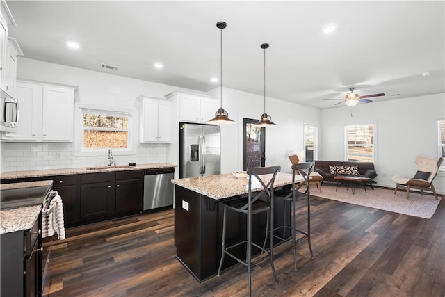 kitchen featuring white cabinets, stainless steel appliances, pendant lighting, a kitchen island, and sink