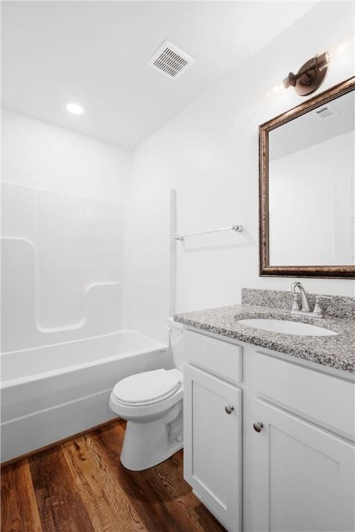 full bathroom with hardwood / wood-style floors,  shower combination, vanity, and toilet