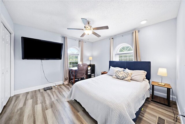 1761 Wire Rd Unit 409, Auburn, AL 36830 - bedroom with a closet, multiple windows, a textured ceiling, wood finished floors, and a ceiling fan