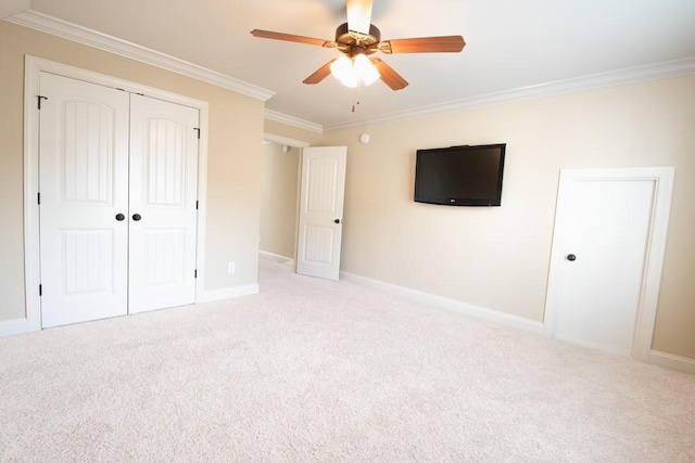 unfurnished bedroom featuring crown molding, light colored carpet, ceiling fan, and a closet