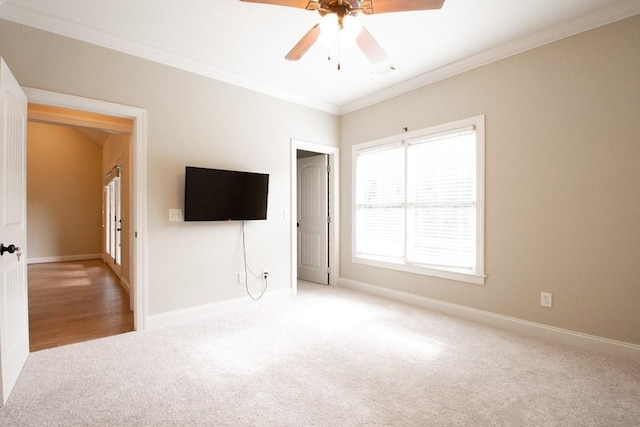 unfurnished bedroom featuring light colored carpet, ornamental molding, and ceiling fan