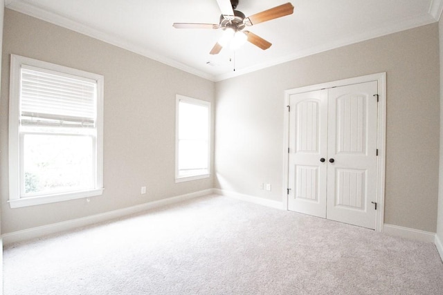 spare room with carpet floors, ornamental molding, and ceiling fan