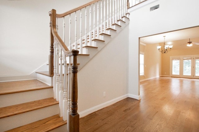 staircase featuring hardwood / wood-style flooring, a towering ceiling, and a notable chandelier