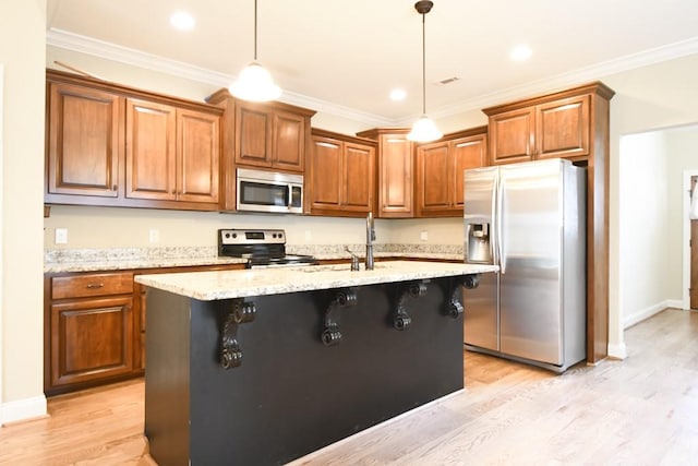 kitchen with appliances with stainless steel finishes, decorative light fixtures, a breakfast bar, and an island with sink