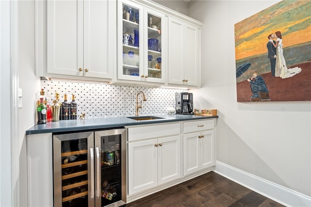 bar featuring a sink, beverage cooler, indoor wet bar, baseboards, and backsplash