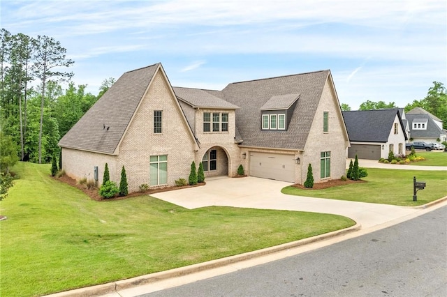 french country style house with roof with shingles, brick siding, a garage, a front yard, and driveway