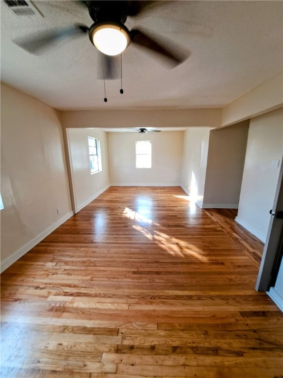 unfurnished room with ceiling fan, a textured ceiling, and light wood-type flooring