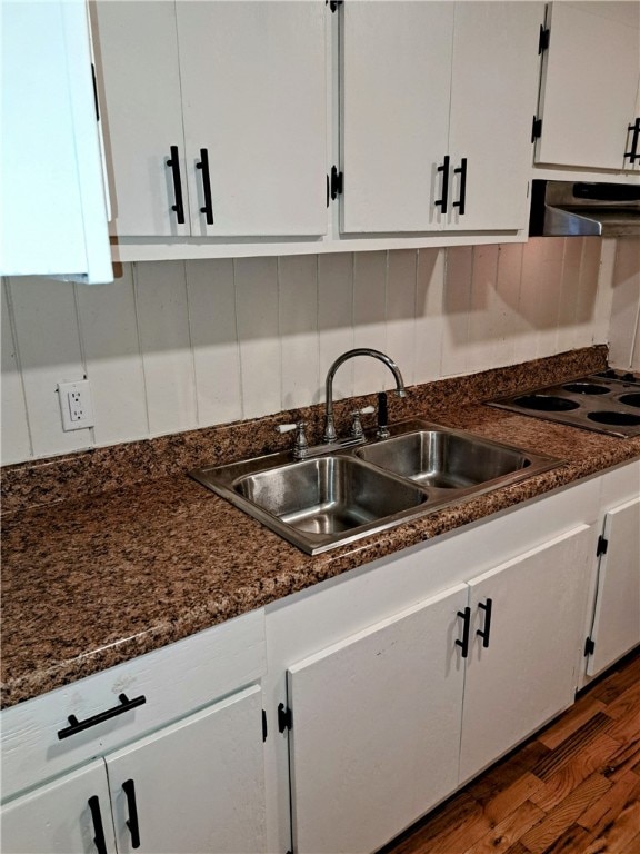 kitchen with sink, dark stone countertops, dark hardwood / wood-style flooring, white cabinets, and stove