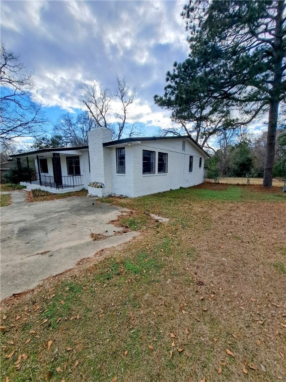 back of house featuring covered porch and a lawn