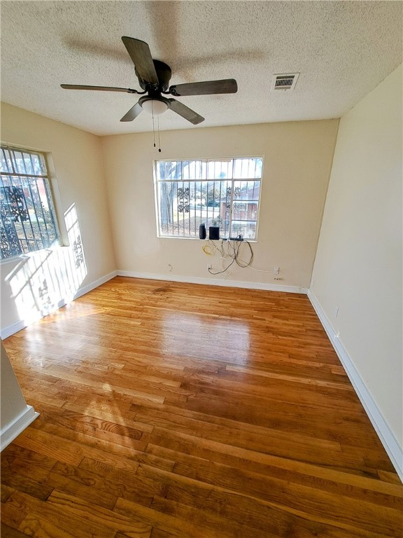 spare room featuring wood-type flooring, ceiling fan, and a textured ceiling