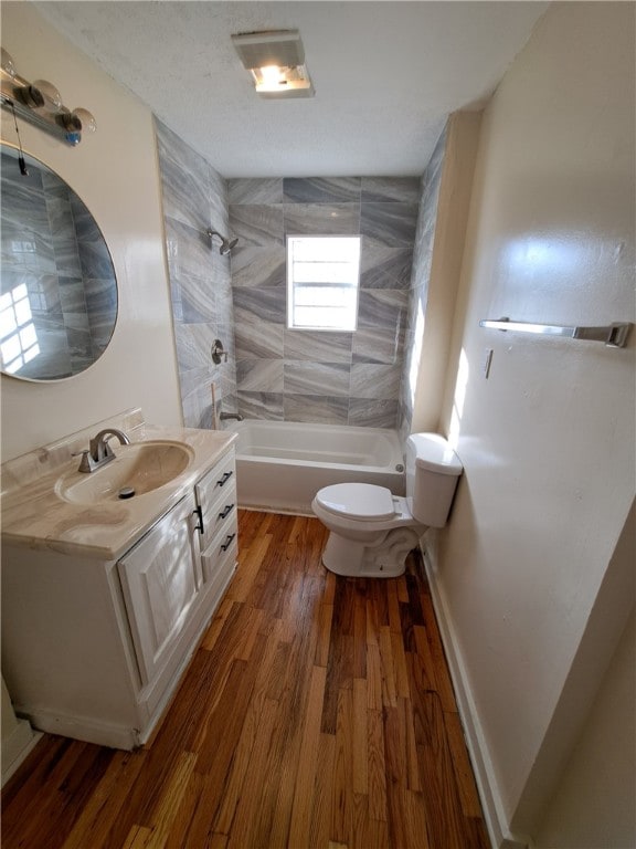 full bathroom with hardwood / wood-style flooring, vanity, toilet, and tiled shower / bath