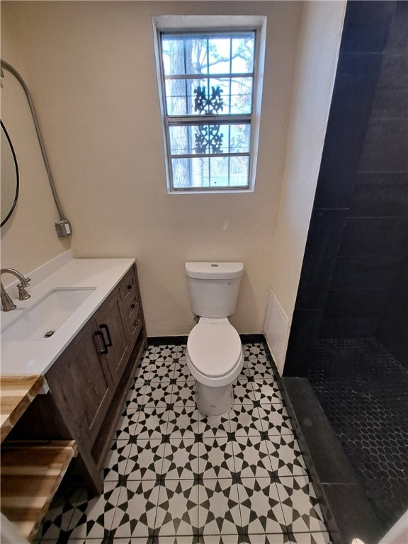 bathroom with vanity, tiled shower, and toilet