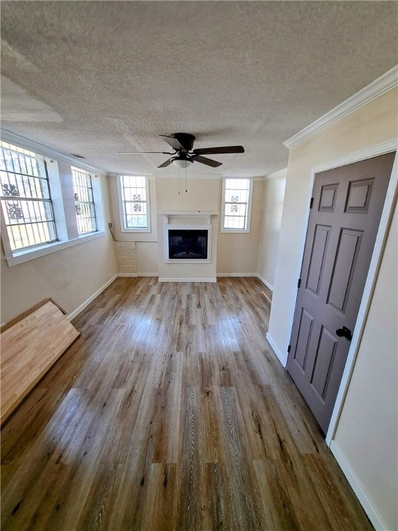 unfurnished living room featuring a healthy amount of sunlight, crown molding, light hardwood / wood-style floors, and a textured ceiling