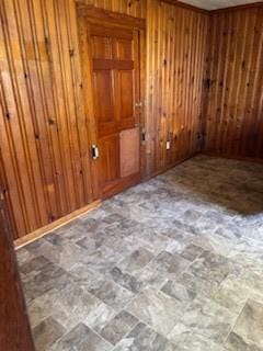 spare room featuring wood walls and stone finish floor