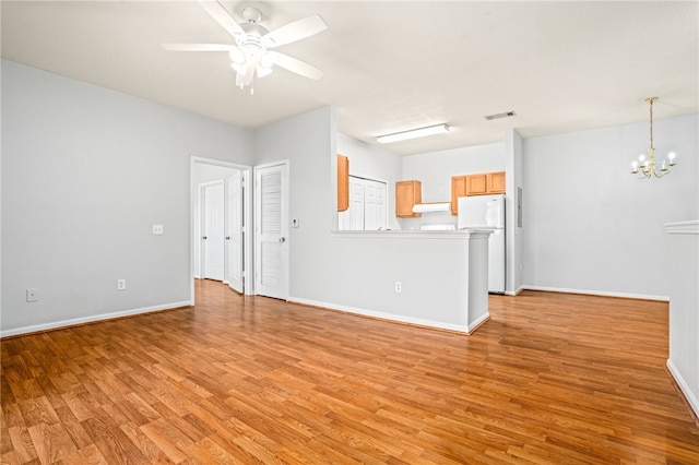 unfurnished living room featuring ceiling fan with notable chandelier and light hardwood / wood-style floors