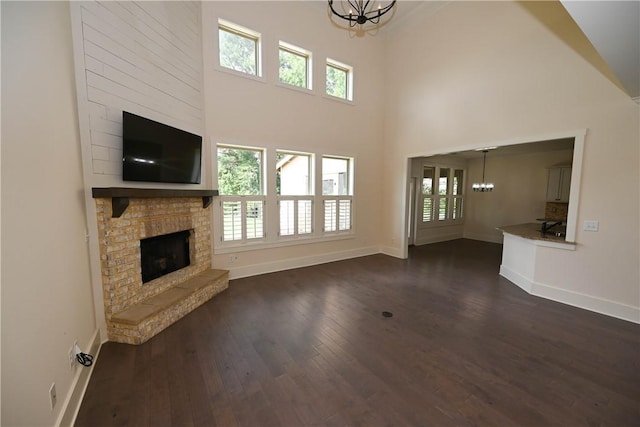 227 Westover St, Auburn, AL 36832 - unfurnished living room featuring a chandelier, dark wood-style floors, a high ceiling, healthy amount of natural light, and a fireplace