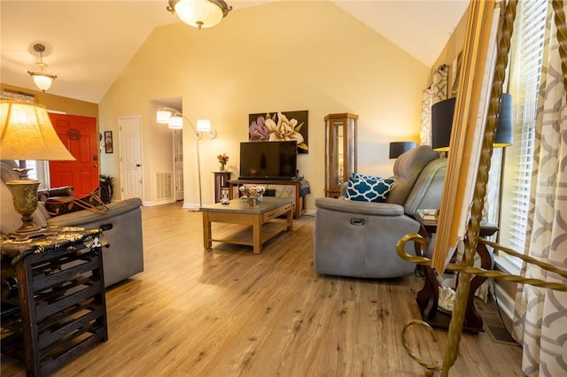 living room featuring baseboards, high vaulted ceiling, and light wood-style flooring